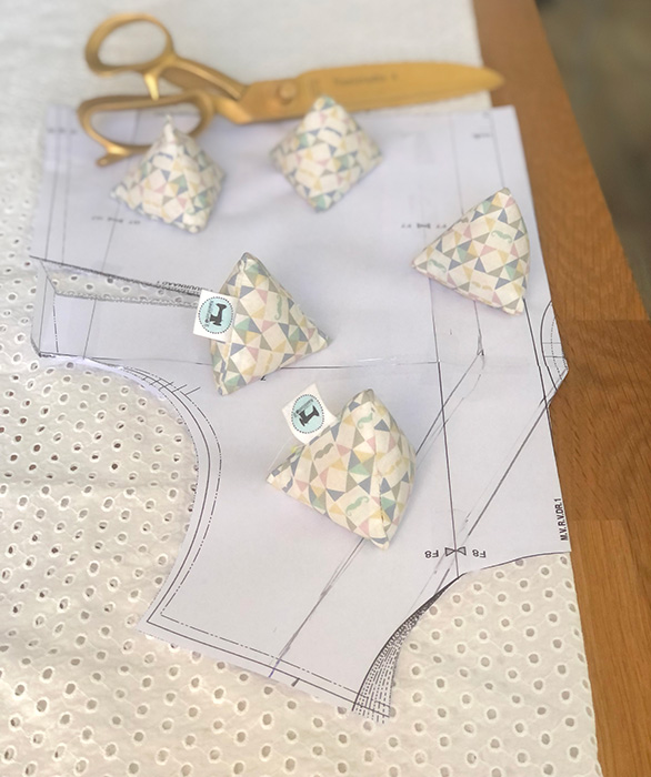 Een baby zit op een houten vloer en knuffelt een konijnenknuffeldoekje met bloemenprintoren en een lichtblauwe wafelstof.